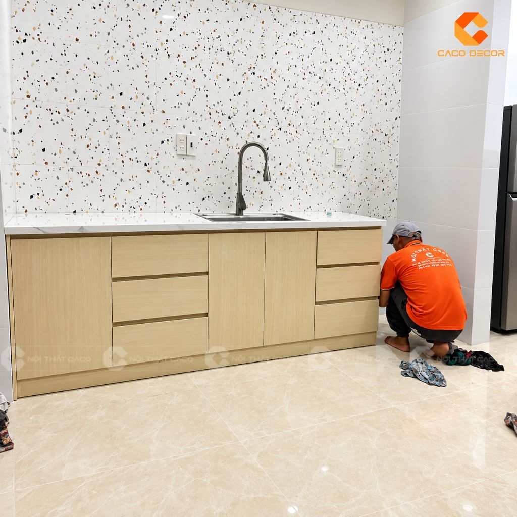 Tủ bếp dưới vân gỗ sáng với mặt bàn trắng tại nhà anh Hiệp